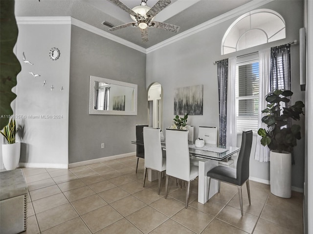 tiled dining room with ceiling fan and crown molding