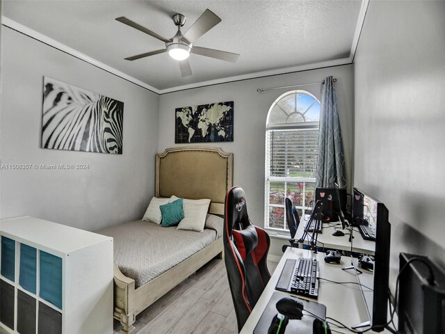 bedroom featuring light hardwood / wood-style floors, ceiling fan, a textured ceiling, and crown molding