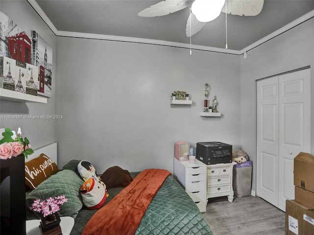 bedroom with ceiling fan, a textured ceiling, a closet, ornamental molding, and light hardwood / wood-style flooring