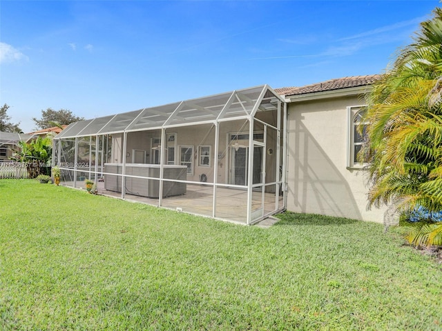 rear view of property with a yard, a patio area, and glass enclosure