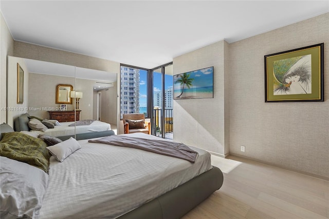 bedroom with a wall of windows and light hardwood / wood-style flooring