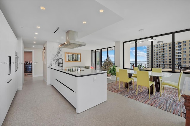 kitchen with black electric stovetop, white cabinets, and island exhaust hood