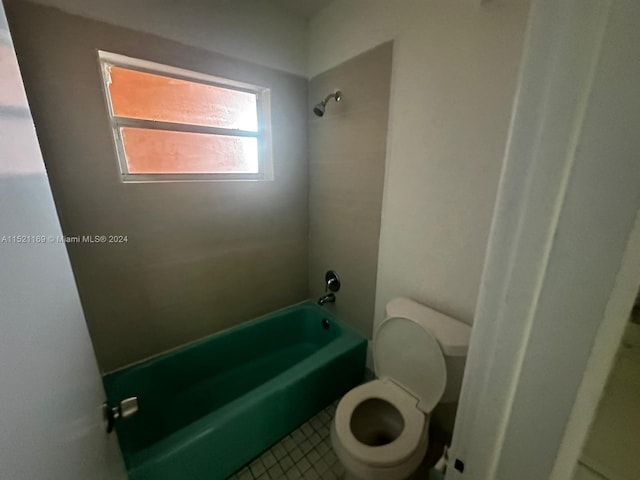 bathroom featuring tiled shower / bath combo, tile floors, and toilet