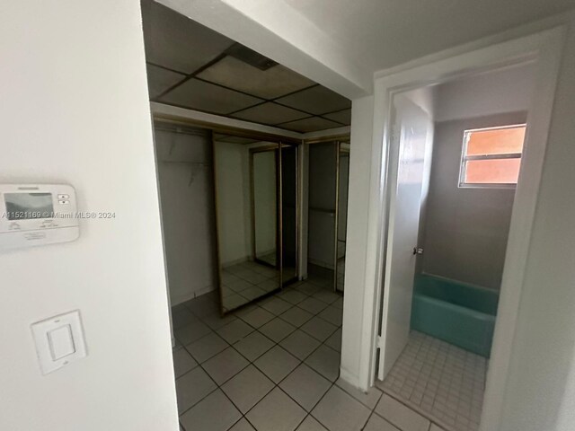 corridor with a paneled ceiling and light tile floors