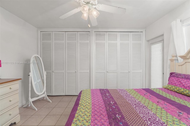 bedroom featuring ceiling fan, light tile patterned floors, and multiple closets