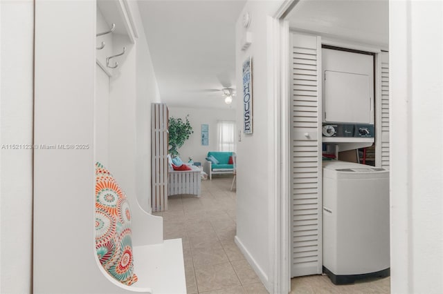 hall featuring light tile patterned flooring and stacked washer / dryer