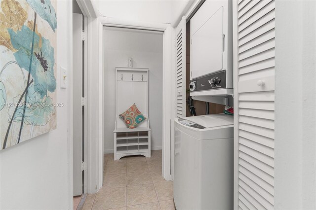 laundry area featuring light tile patterned flooring and stacked washer / drying machine