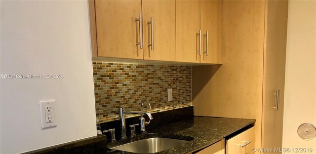 kitchen with backsplash, light brown cabinetry, sink, and dark stone counters