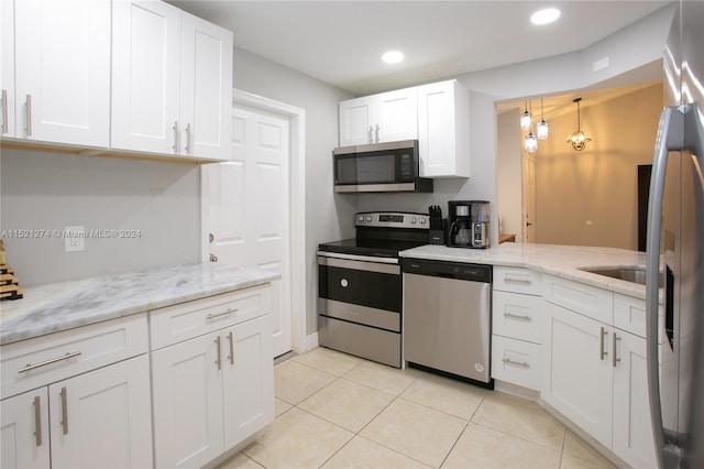 kitchen with light tile flooring, hanging light fixtures, stainless steel appliances, and white cabinetry