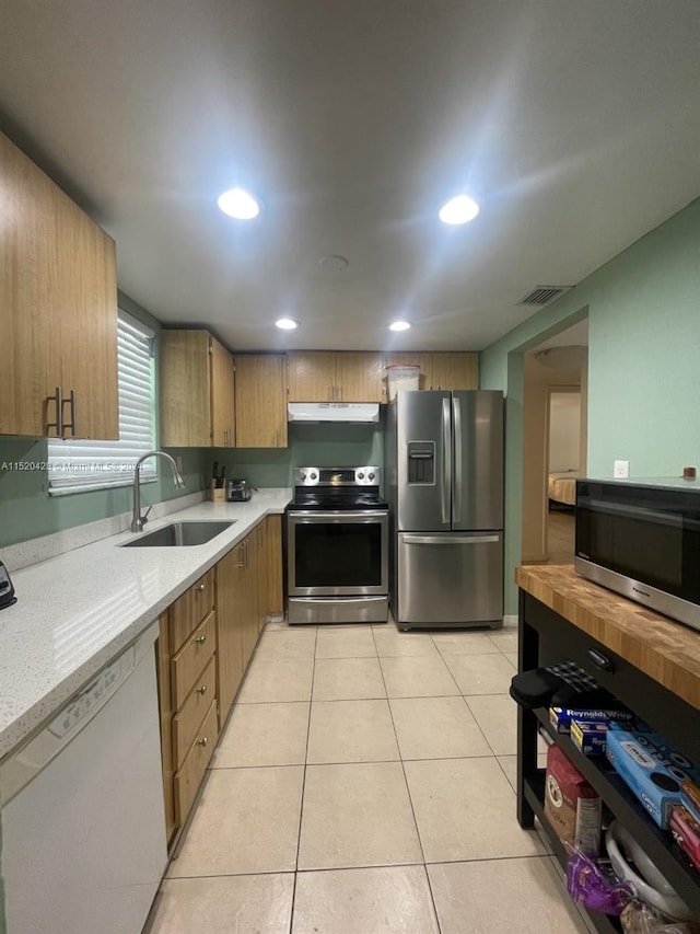 kitchen featuring light tile floors, light stone counters, sink, and stainless steel appliances