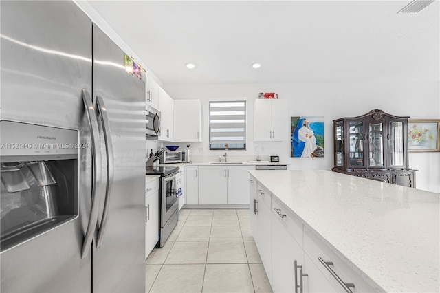 kitchen with white cabinetry, sink, light stone counters, light tile patterned floors, and appliances with stainless steel finishes