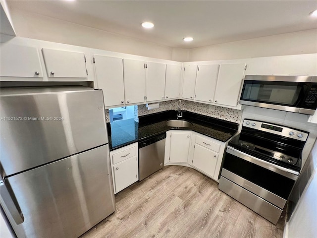 kitchen featuring light hardwood / wood-style flooring, white cabinetry, appliances with stainless steel finishes, backsplash, and sink