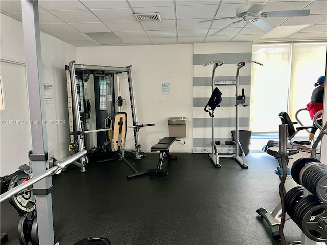 exercise room with ceiling fan, a wealth of natural light, and a paneled ceiling