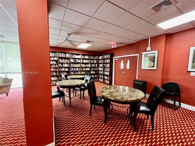 dining room featuring ceiling fan, dark carpet, and a paneled ceiling