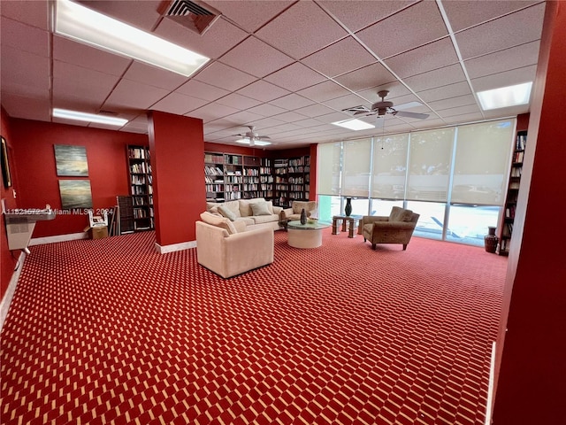 interior space featuring carpet floors, expansive windows, ceiling fan, and a drop ceiling