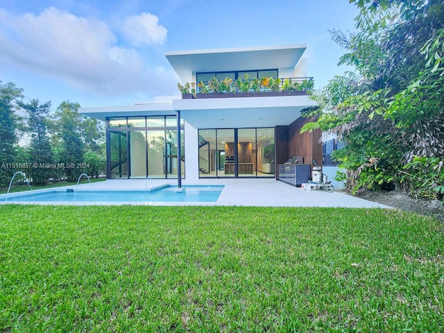 rear view of house with a lawn, a balcony, pool water feature, and a patio area