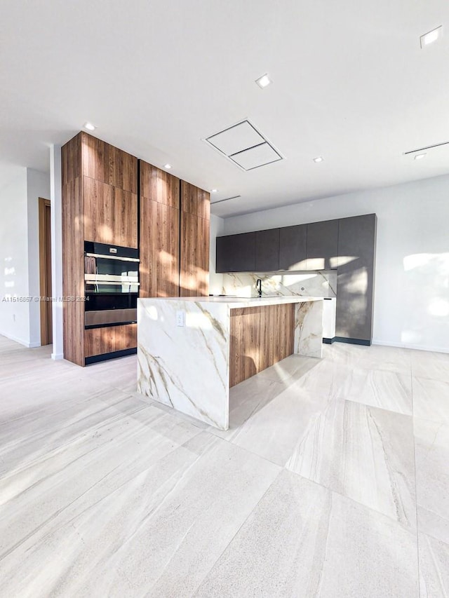 kitchen with oven, a spacious island, and tasteful backsplash