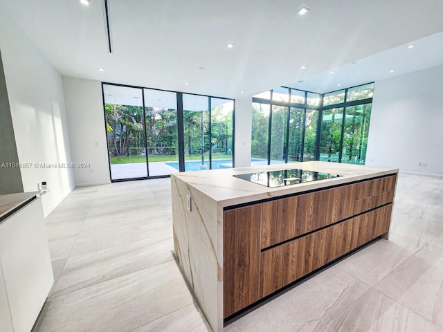 kitchen featuring a center island with sink, expansive windows, and black electric cooktop