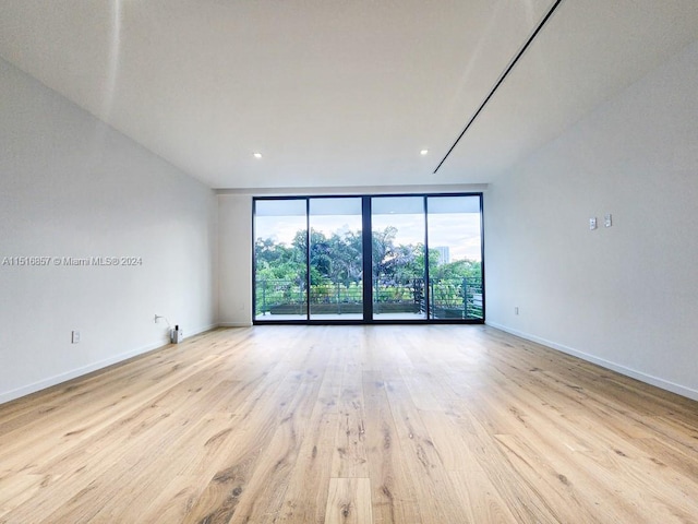 unfurnished room featuring light hardwood / wood-style flooring and a wall of windows