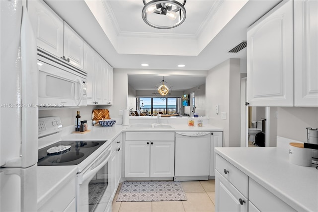 kitchen with white appliances, white cabinetry, and a tray ceiling