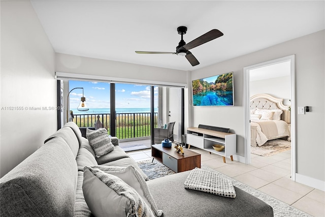 tiled living room featuring a water view and ceiling fan