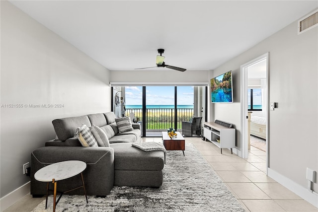 tiled living room featuring a water view and ceiling fan