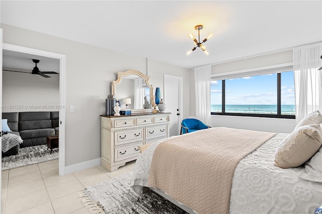 bedroom with light tile floors, a chandelier, and a water view