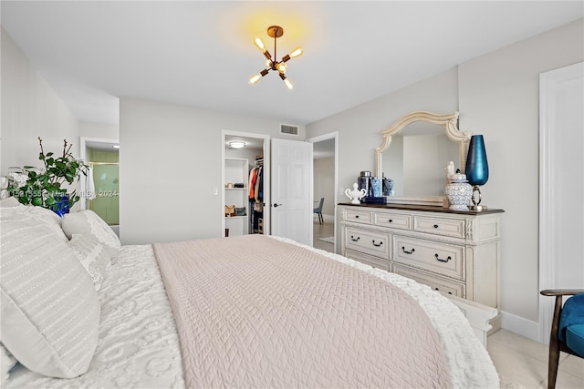 bedroom featuring a closet, an inviting chandelier, a spacious closet, and light colored carpet