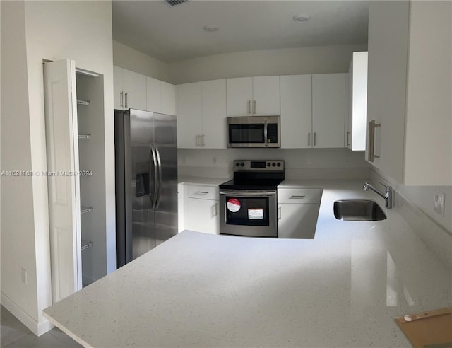 kitchen with stainless steel appliances, white cabinetry, and sink