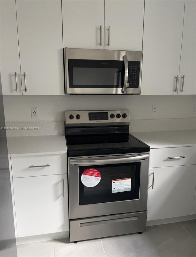 kitchen with white cabinets, light tile flooring, and stainless steel appliances