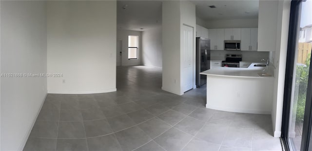 kitchen with light tile flooring, white cabinets, appliances with stainless steel finishes, and a wealth of natural light