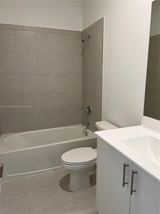 full bathroom featuring tiled shower / bath, toilet, tile floors, and vanity