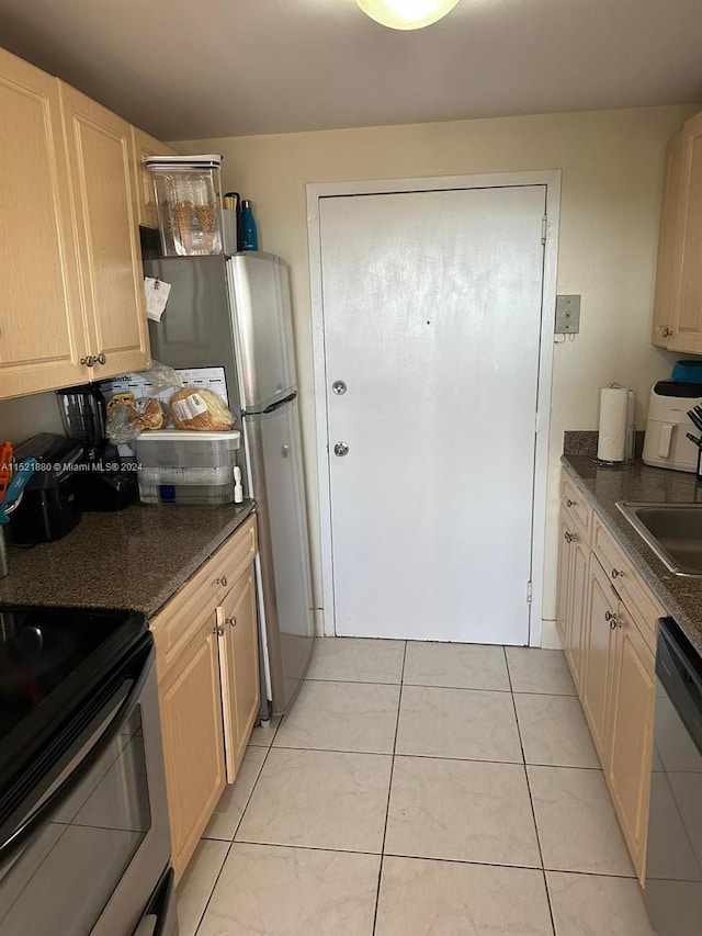 kitchen featuring light tile floors, appliances with stainless steel finishes, and light brown cabinetry