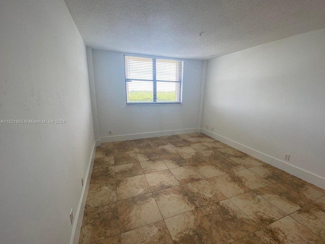 tiled spare room featuring a textured ceiling