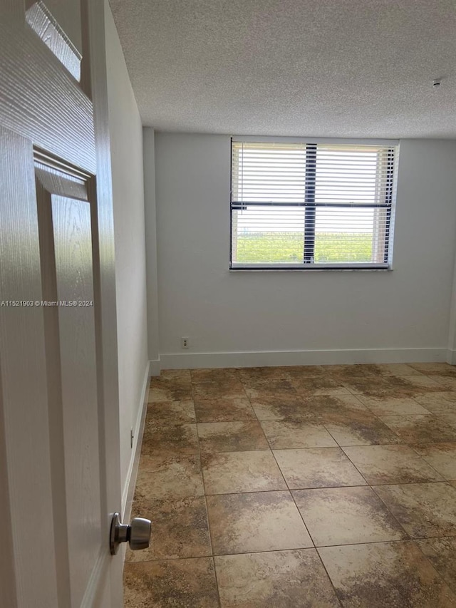 tiled spare room with a textured ceiling