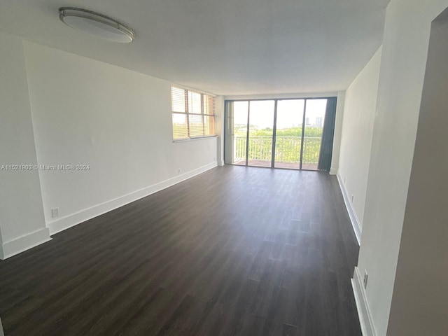 spare room with dark hardwood / wood-style floors and a wall of windows