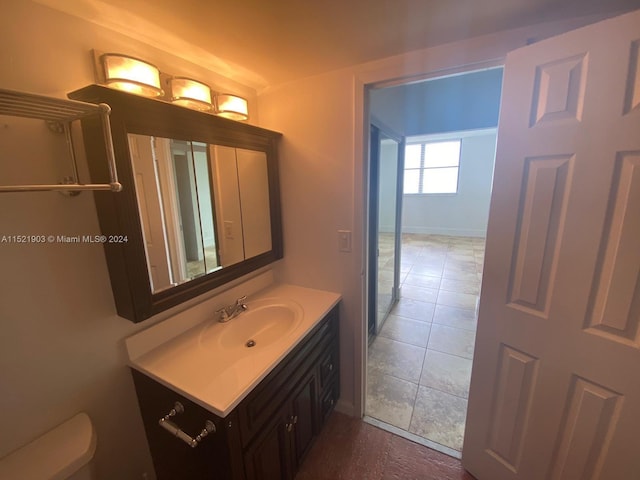 bathroom with toilet, large vanity, and tile flooring