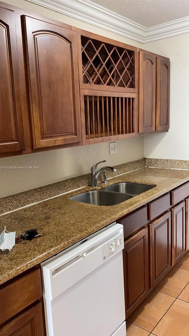 kitchen with sink, light tile floors, dark stone counters, ornamental molding, and white dishwasher