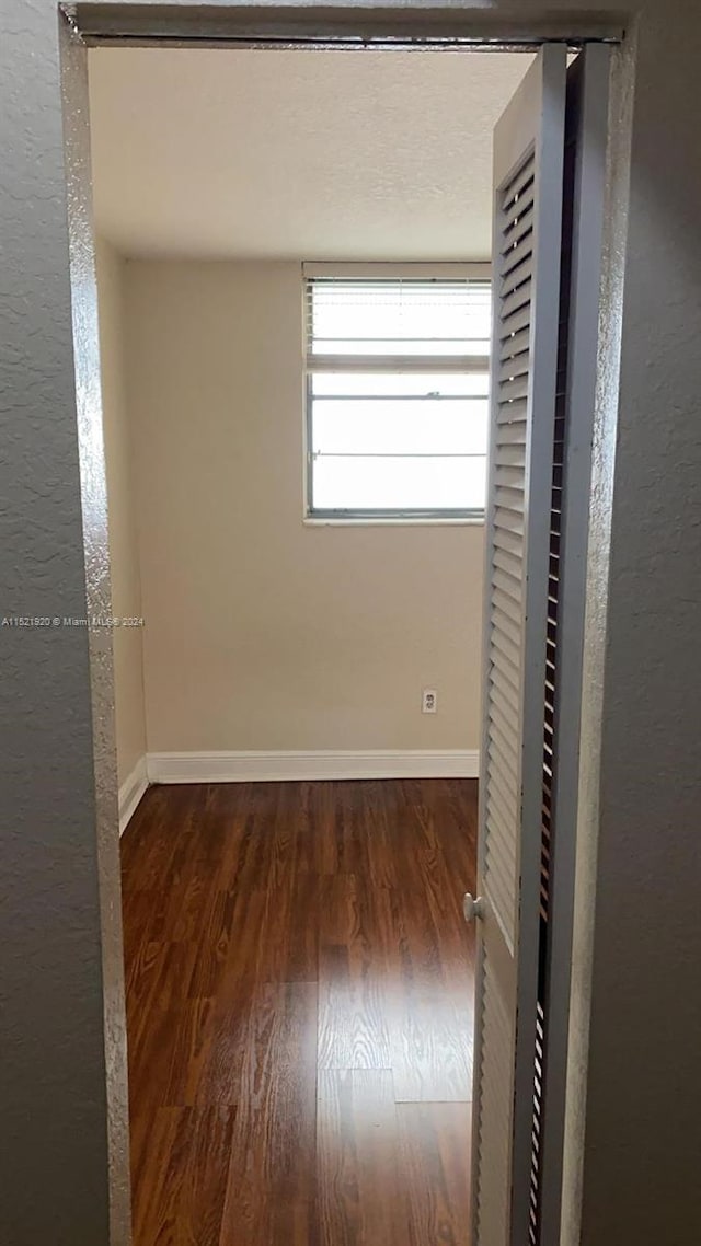 unfurnished room with dark wood-type flooring