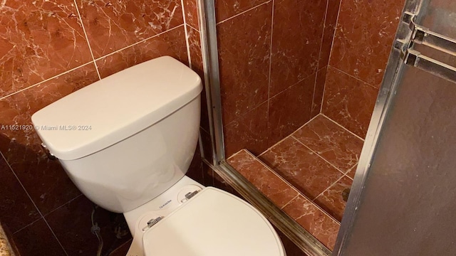 bathroom featuring toilet and tile walls