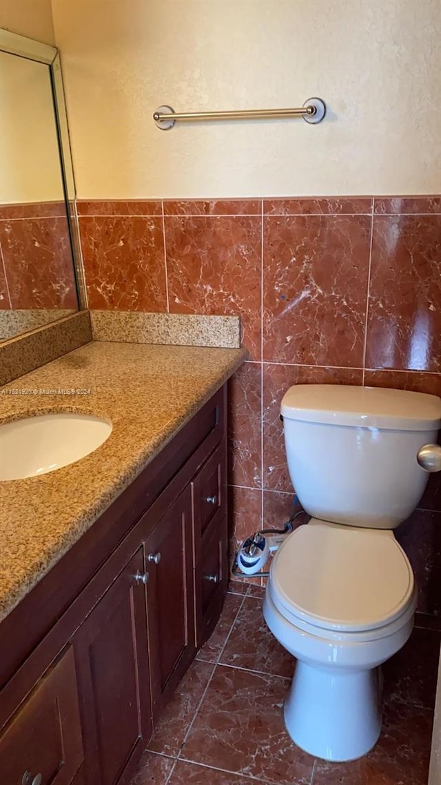 bathroom featuring tile walls, toilet, vanity, and tile flooring