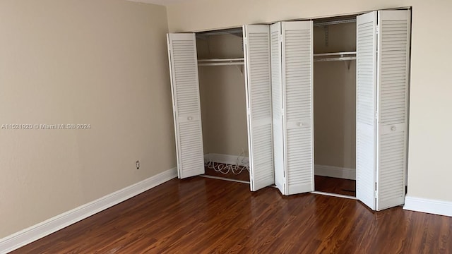 unfurnished bedroom with dark hardwood / wood-style floors and multiple closets