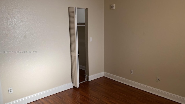 unfurnished bedroom featuring a closet and dark wood-type flooring