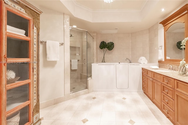 bathroom with tile patterned flooring, a raised ceiling, separate shower and tub, ornamental molding, and vanity