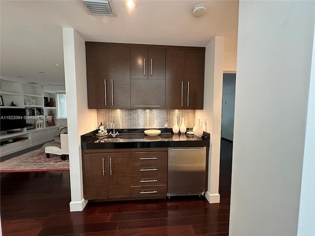 kitchen with backsplash, dark brown cabinetry, and dark wood-type flooring