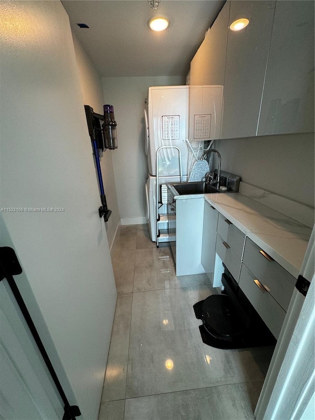 kitchen with light tile flooring, light stone countertops, gray cabinets, and sink