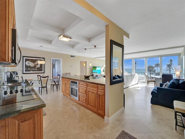 kitchen with sink, wall oven, decorative light fixtures, light tile patterned flooring, and coffered ceiling