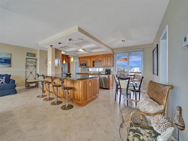 kitchen featuring a breakfast bar area, dishwashing machine, tasteful backsplash, kitchen peninsula, and decorative light fixtures