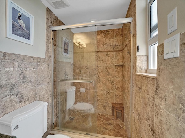 bathroom featuring tile walls, toilet, and an enclosed shower