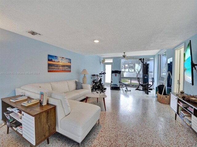 living room with ceiling fan and a textured ceiling